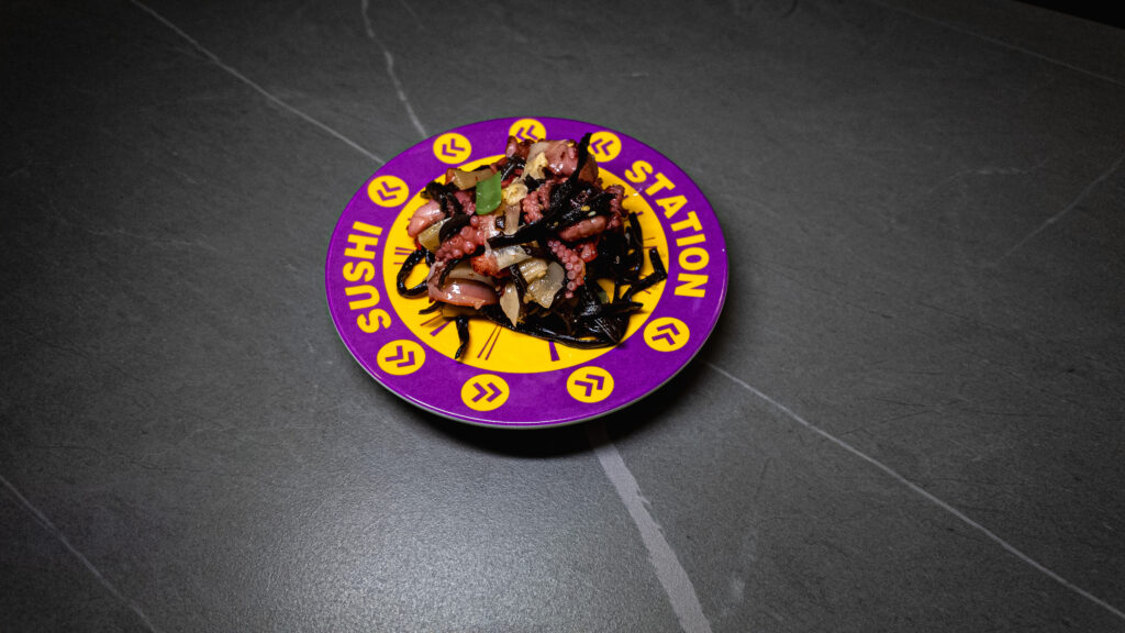Seafood dish with octopus and mussels served on purple Sushi Station branded plate at restaurant