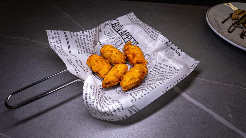 Golden fried chicken nuggets served on newspaper in a black skillet at CROWDFAVORITES restaurant