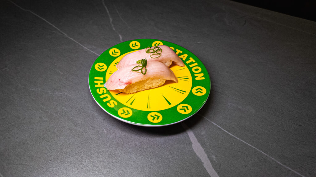 Fresh sushi nigiri served on green conveyor belt sushi station plate at restaurant