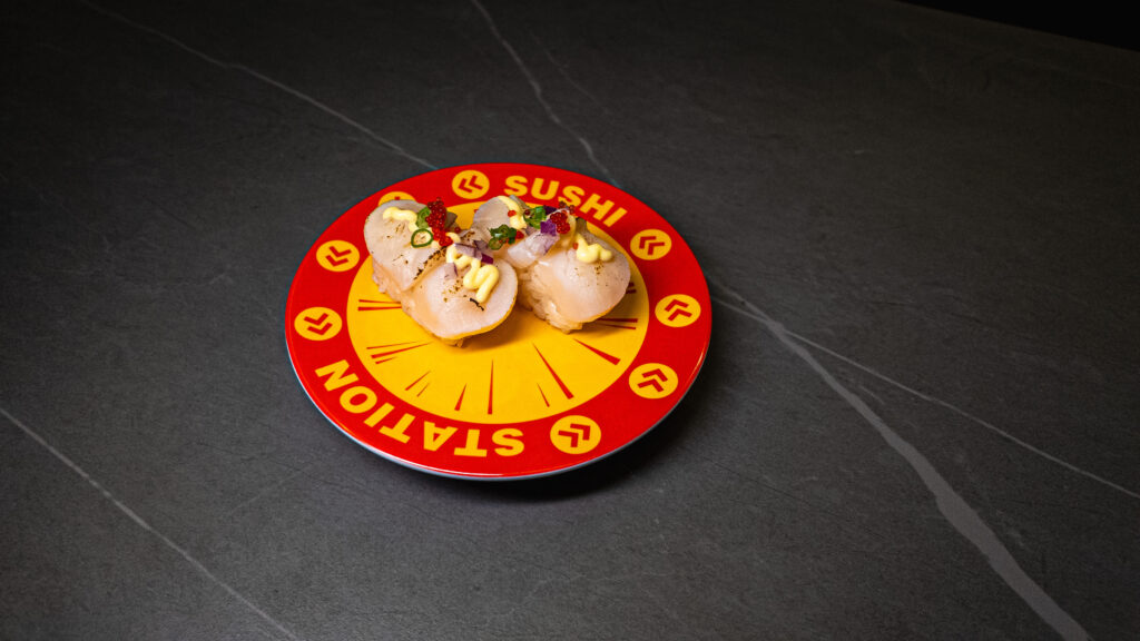 Fresh sushi on colorful conveyor belt plate at Japanese restaurant with red and yellow branded design