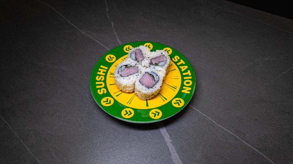 Sushi Station plate with four sushi rolls on dark table, perfect for CROWDFAVORITES restaurant menu or delivery promotion.