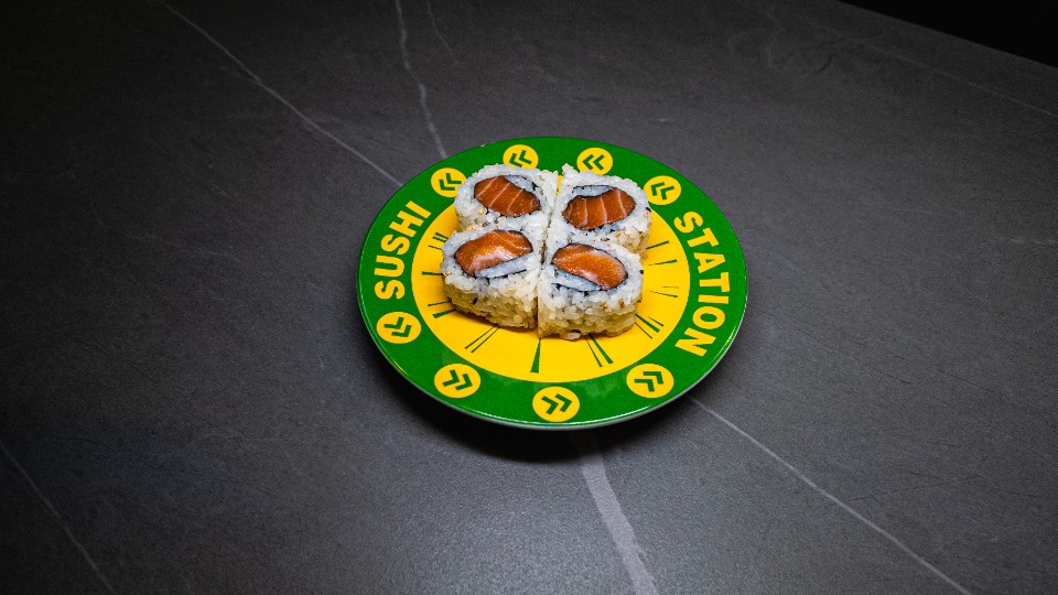Sushi Station plate with four salmon rolls on dark table, perfect for CROWDFAVORITES restaurant menu and sushi lovers.