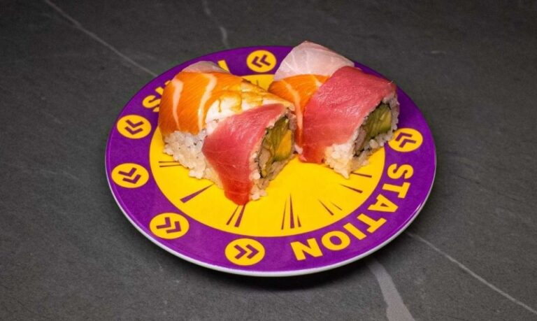 Sushi rolls with tuna and salmon on purple "Station" plate at CROWDFAVORITES restaurant, perfect for sushi lovers.