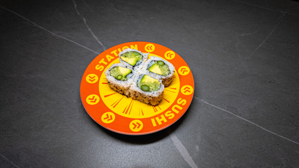 Four avocado sushi rolls on vibrant orange "Station Sushi" plate, served at CROWDFAVORITES restaurant.