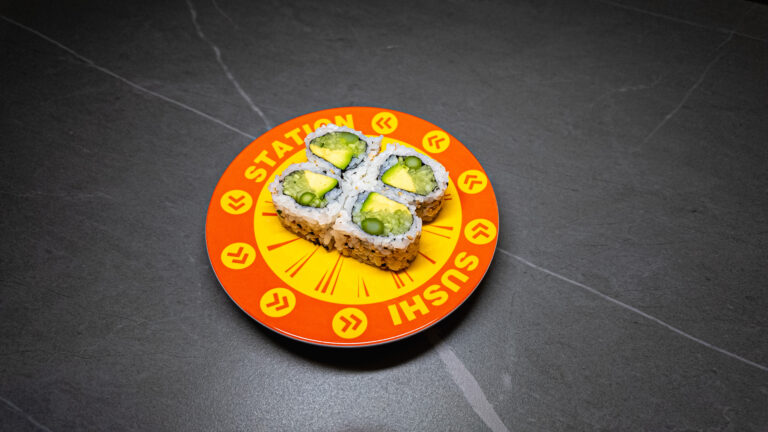 Four avocado sushi rolls on vibrant orange "Station Sushi" plate, perfect for CROWDFAVORITES restaurant menu.