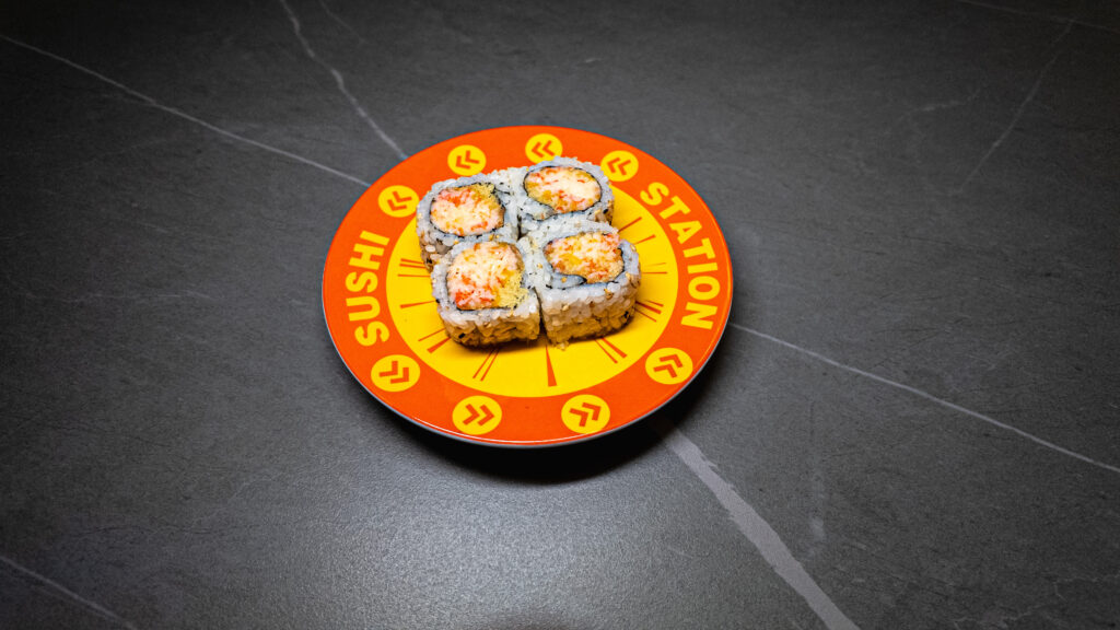 Four sushi rolls on vibrant orange "Sushi Station" plate, served at CROWDFAVORITES restaurant — fresh, crispy, and appetiz...