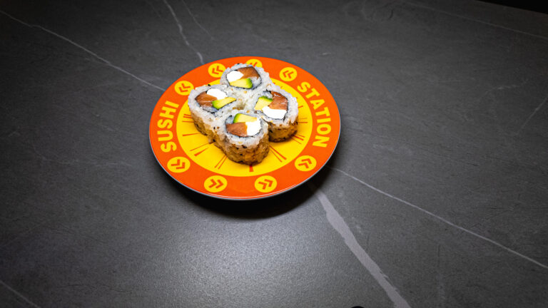 Sushi Station plate with four sushi rolls featuring salmon, avocado, and cream cheese on dark table, perfect for restauran...