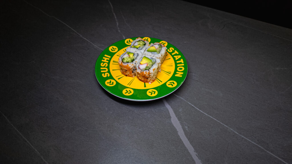 Sushi Station plate with California rolls on dark marble table, perfect for CROWDFAVORITES restaurant menu or delivery promo.