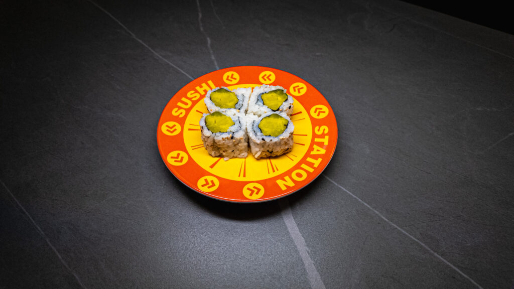Four cucumber sushi rolls on vibrant orange "Sushi Station" plate, perfect for restaurant menu or food blog SEO.