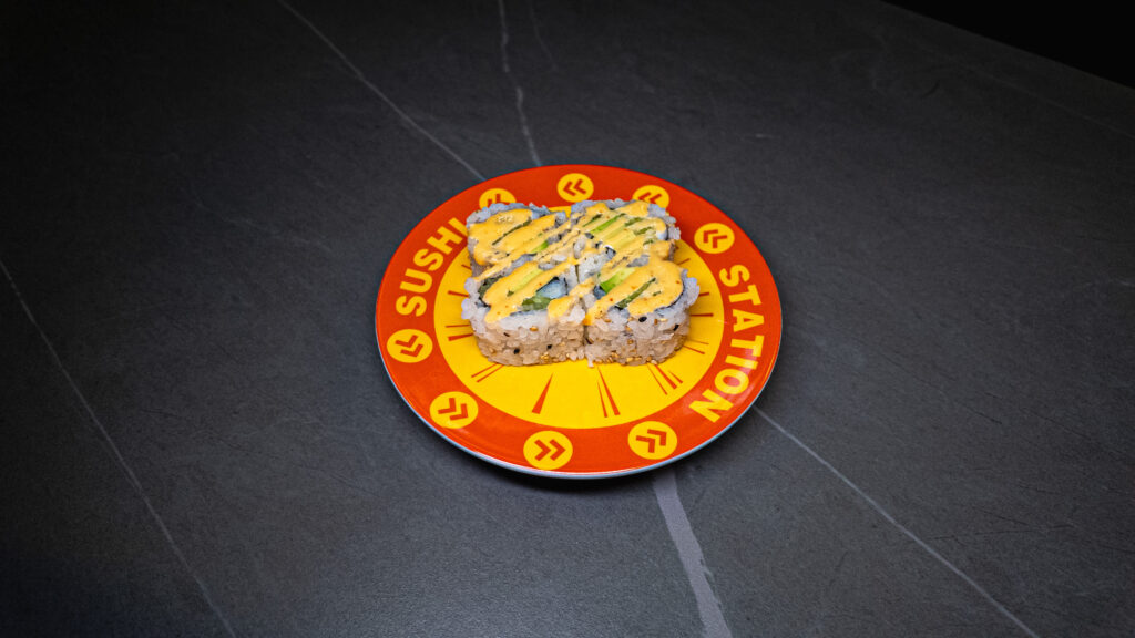 Sushi Station plate with avocado rolls drizzled in sauce, served at CROWDFAVORITES restaurant on dark slate table.