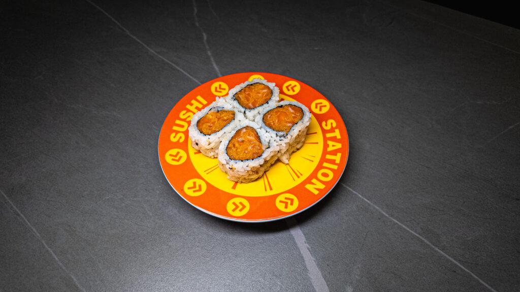 Four spicy tuna sushi rolls on vibrant orange "Sushi Station" plate, served at CROWDFAVORITES restaurant.