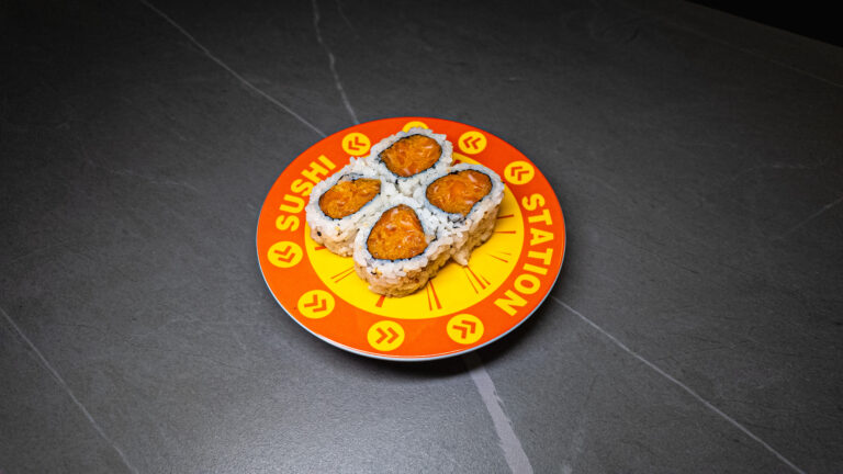 Four spicy tuna sushi rolls on vibrant orange "Sushi Station" plate, served at CROWDFAVORITES restaurant.