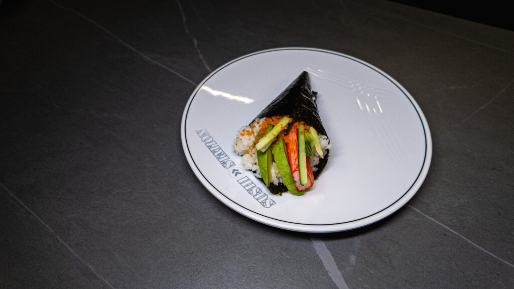 Sushi Station hand roll with avocado, crab, cucumber, and tobiko on branded plate, served at CROWDFAVORITES restaurant