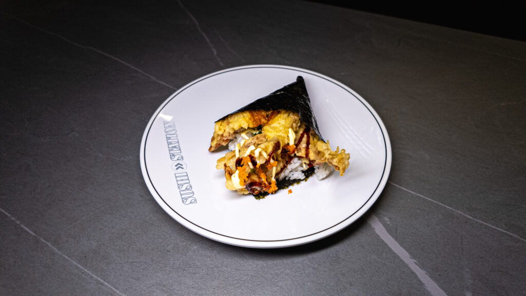 Crispy tempura onigiri with sauce drizzle, served on Sushi Station plate at CROWDFAVORITES restaurant.