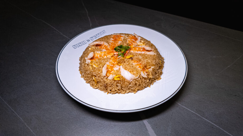 Crab fried rice with egg and green onions on white plate at CROWDFAVORITES restaurant, perfect for sushi lovers seeking bo...
