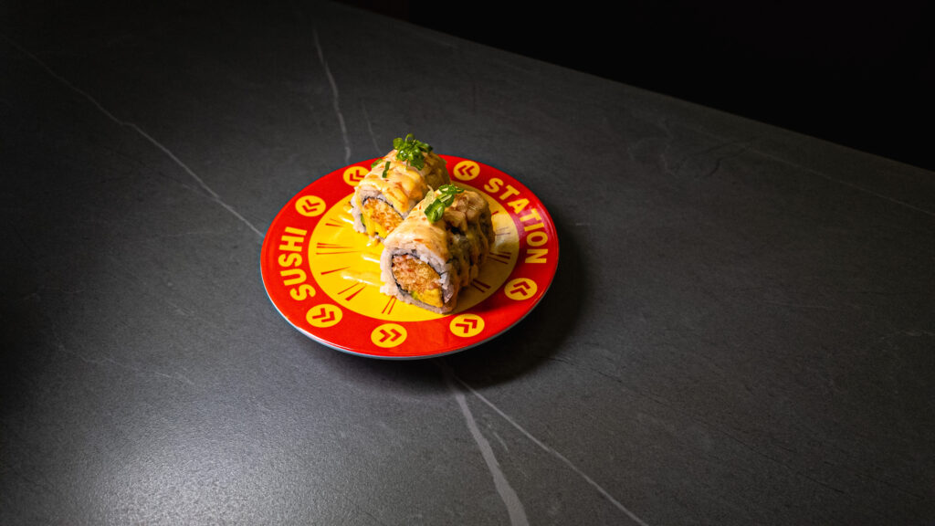 Fresh sushi rolls with avocado and green onions served on red branded plate at restaurant