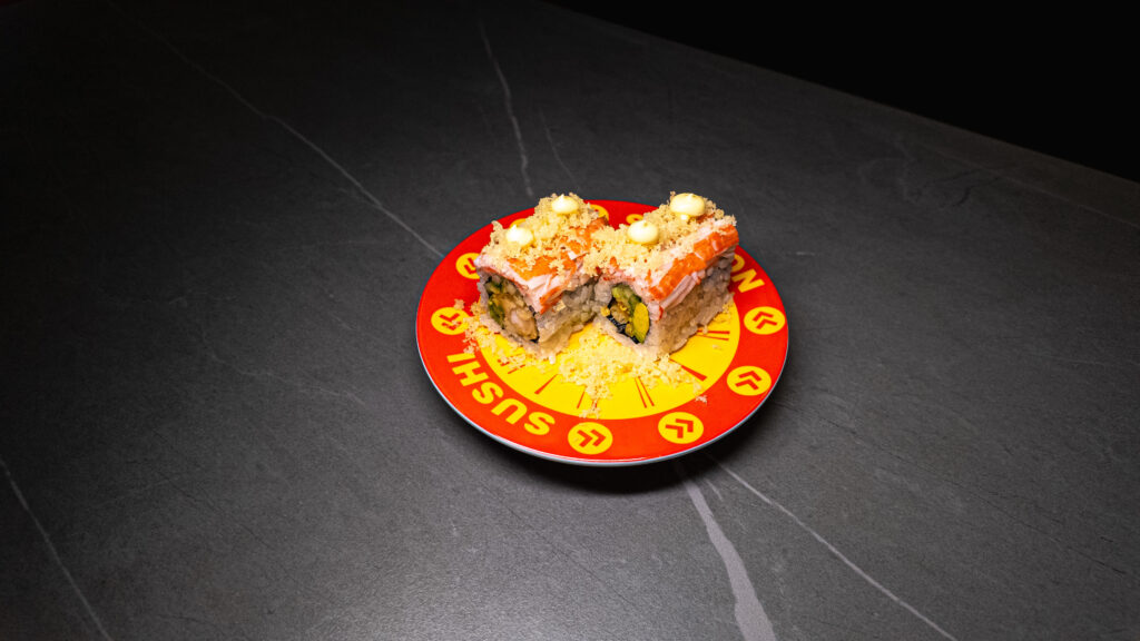 Sushi rolls with crab, avocado, and crispy topping on red "SUSHI" plate at CROWDFAVORITES restaurant