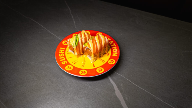 Sushi Station plate with salmon rolls, avocado, and sauce on dark table — CrowdFavorites restaurant favorite dish
