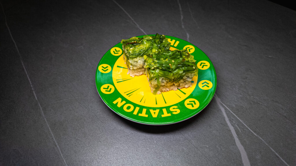 Green seaweed sushi on vibrant yellow and green "STATION" plate, served at CROWDFAVORITES restaurant.