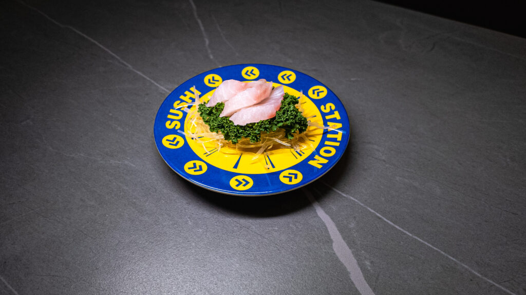 Sushi Station plate with fresh sashimi, green garnish, and shredded daikon on dark table — CROWDFAVORITES restaurant favorite