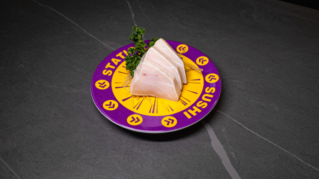 Fresh sashimi on purple and yellow “Sushi Station” plate, garnished with greens, served at CROWDFAVORITES restaurant.