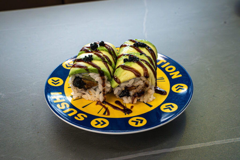 Avocado sushi rolls with caviar and sauce on a branded plate at CROWDFAVORITES restaurant