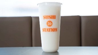 Sushi Station branded cup with orange logo on table, perfect for restaurant takeout or dine-in experience