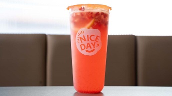 Vibrant orange fruit drink in clear cup with “NICE DAY” logo, served at CROWDFAVORITES restaurant, perfect for refreshing ...