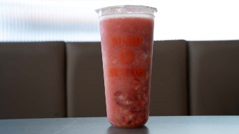 Fresh watermelon smoothie in branded cup at CROWDFAVORITES restaurant, vibrant red with visible fruit chunks, served on table