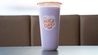 Purple iced drink in branded cup with "NICE DAY" logo, served at CROWDFAVORITES restaurant on table near booth seating