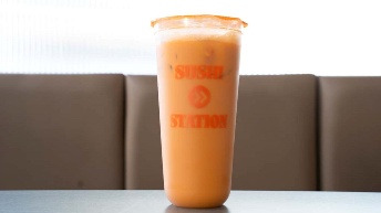 Orange smoothie in branded cup from CROWDFAVORITES restaurant, served on table with booth seating background