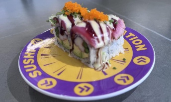 Sushi roll with orange fish roe and purple sauce on purple restaurant plate at CROWDFAVORITES
