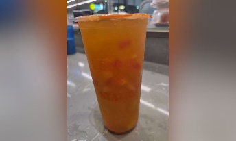 Orange iced tea with ice cubes in branded cup at CROWDFAVORITES restaurant, perfect refreshing drink choice